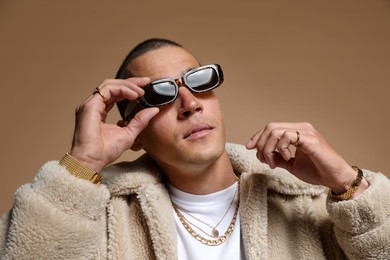 Photo of Fashionable portrait of handsome man in stylish outfit on brown background