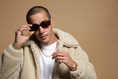 Photo of Fashionable portrait of handsome man in stylish outfit on brown background, space for text