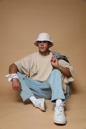 Photo of Fashionable portrait of handsome man in stylish outfit on brown background