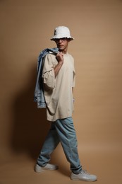 Photo of Fashionable portrait of handsome man in stylish outfit on brown background