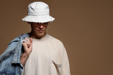 Photo of Fashionable portrait of handsome man in stylish outfit on brown background, space for text
