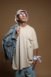 Photo of Fashionable portrait of handsome man in stylish outfit on brown background