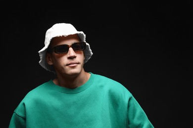 Photo of Fashionable portrait of handsome man in stylish outfit on black background, space for text