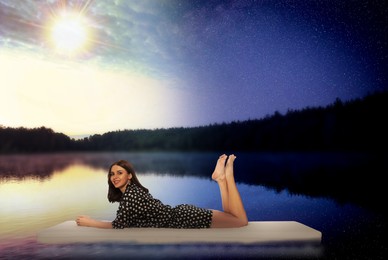 Image of Smiling young woman lying on comfortable mattress in river at evening