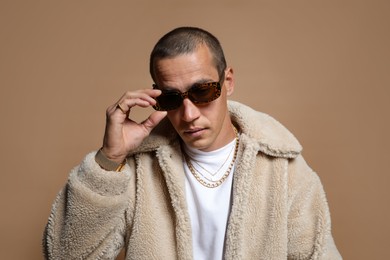Photo of Fashionable portrait of handsome man in stylish outfit on brown background