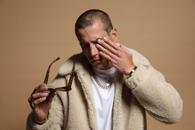 Photo of Fashionable portrait of handsome man in stylish outfit on brown background