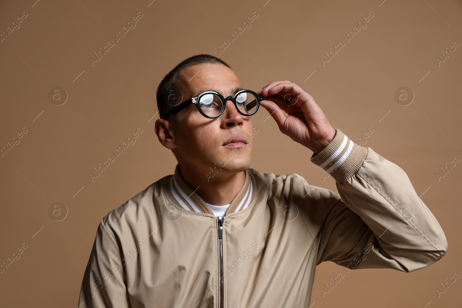 Fashionable portrait of handsome man in stylish outfit on brown background Photo of Fashionable portrait of handsome man in stylish outfit on brown background