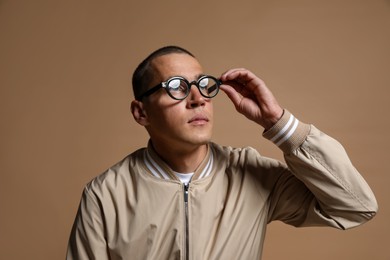 Photo of Fashionable portrait of handsome man in stylish outfit on brown background