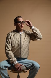 Photo of Fashionable portrait of handsome man in stylish outfit on brown background