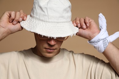 Photo of Fashionable portrait of handsome man in stylish outfit on brown background