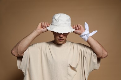 Photo of Fashionable portrait of handsome man in stylish outfit on brown background