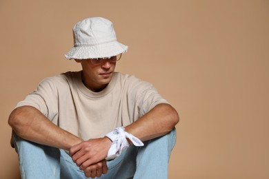Photo of Fashionable portrait of handsome man in stylish outfit on brown background, space for text
