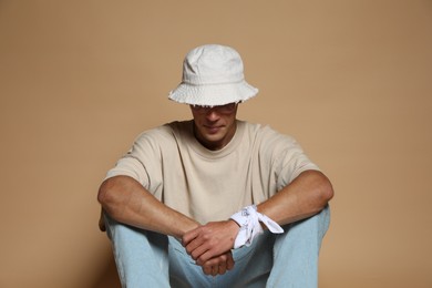 Photo of Fashionable portrait of handsome man in stylish outfit on brown background