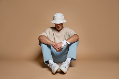 Photo of Fashionable portrait of handsome man in stylish outfit on brown background