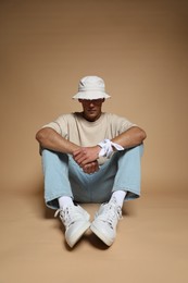 Photo of Fashionable portrait of handsome man in stylish outfit on brown background