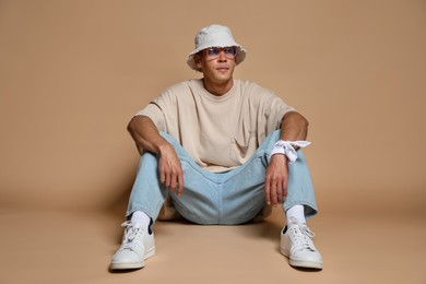 Photo of Fashionable portrait of handsome man in stylish outfit on brown background