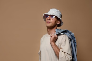 Photo of Fashionable portrait of handsome man in stylish outfit on brown background, space for text