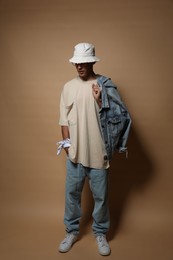 Photo of Fashionable portrait of handsome man in stylish outfit on brown background