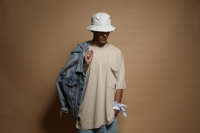 Photo of Fashionable portrait of handsome man in stylish outfit on brown background