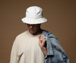Photo of Fashionable portrait of handsome man in stylish outfit on brown background