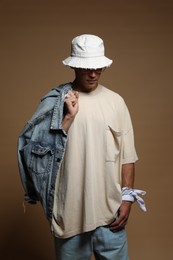 Photo of Fashionable portrait of handsome man in stylish outfit on brown background