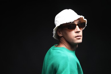 Photo of Fashionable portrait of handsome man in stylish outfit on black background, space for text
