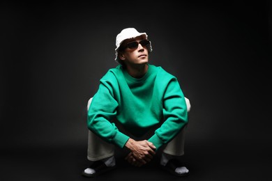 Photo of Fashionable portrait of handsome man in stylish outfit on black background