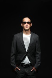 Photo of Fashionable portrait of handsome man in stylish outfit on black background