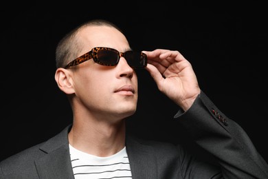 Photo of Fashionable portrait of handsome man in stylish outfit on black background