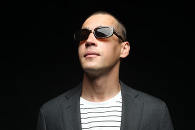 Photo of Fashionable portrait of handsome man in stylish outfit on black background