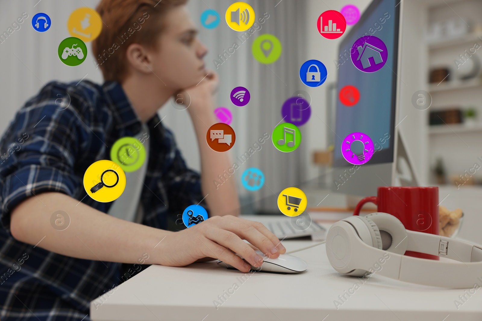 Internet addicted teenager using computer in room. Different icons near him Image of Internet addicted teenager using computer in room. Different icons near him