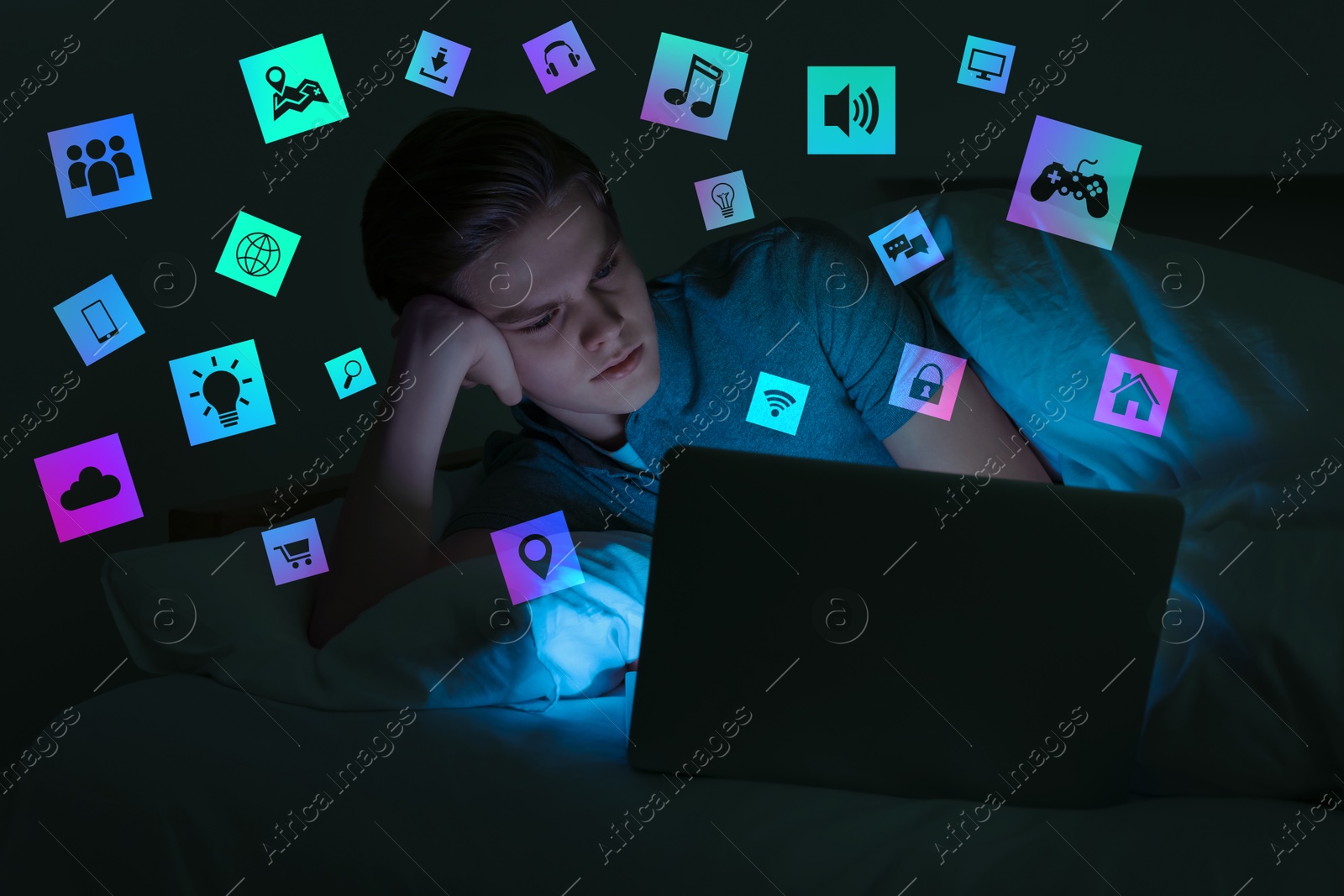 Internet addicted teenager using laptop instead of sleeping in bed at night. Different icons near him Image of Internet addicted teenager using laptop instead of sleeping in bed at night. Different icons near him
