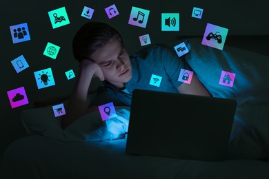 Image of Internet addicted teenager using laptop instead of sleeping in bed at night. Different icons near him