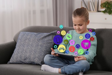 Image of Internet addicted child using tablet computer at home. Different icons flying out of device