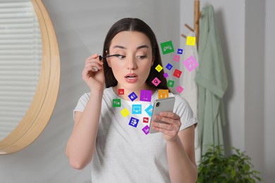 Image of Internet addicted woman using mobile phone while applying mascara at home. Different icons flying out of device