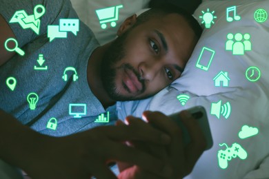Image of Internet addicted man using mobile phone instead of sleeping at night. Different icons near him