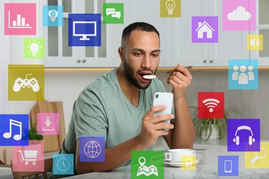 Image of Internet addicted man using mobile phone while eating at home. Different icons around him