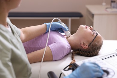 Photo of Sonographer conducting girl's thyroid gland ultrasound examination in clinic, closeup