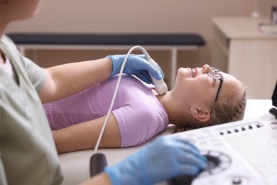 Photo of Sonographer conducting girl's thyroid gland ultrasound examination in clinic, closeup