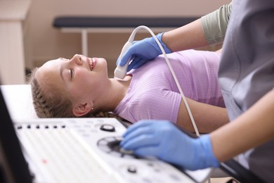 Photo of Sonographer conducting girl's thyroid gland ultrasound examination in clinic, closeup