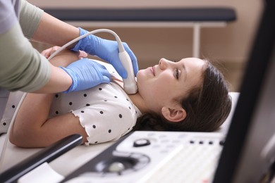 Photo of Sonographer conducting girl's thyroid gland ultrasound examination in clinic, closeup