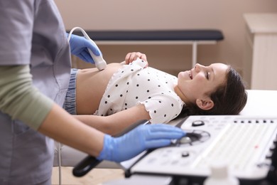 Photo of Sonographer conducting girl's abdominal ultrasound examination in clinic, closeup