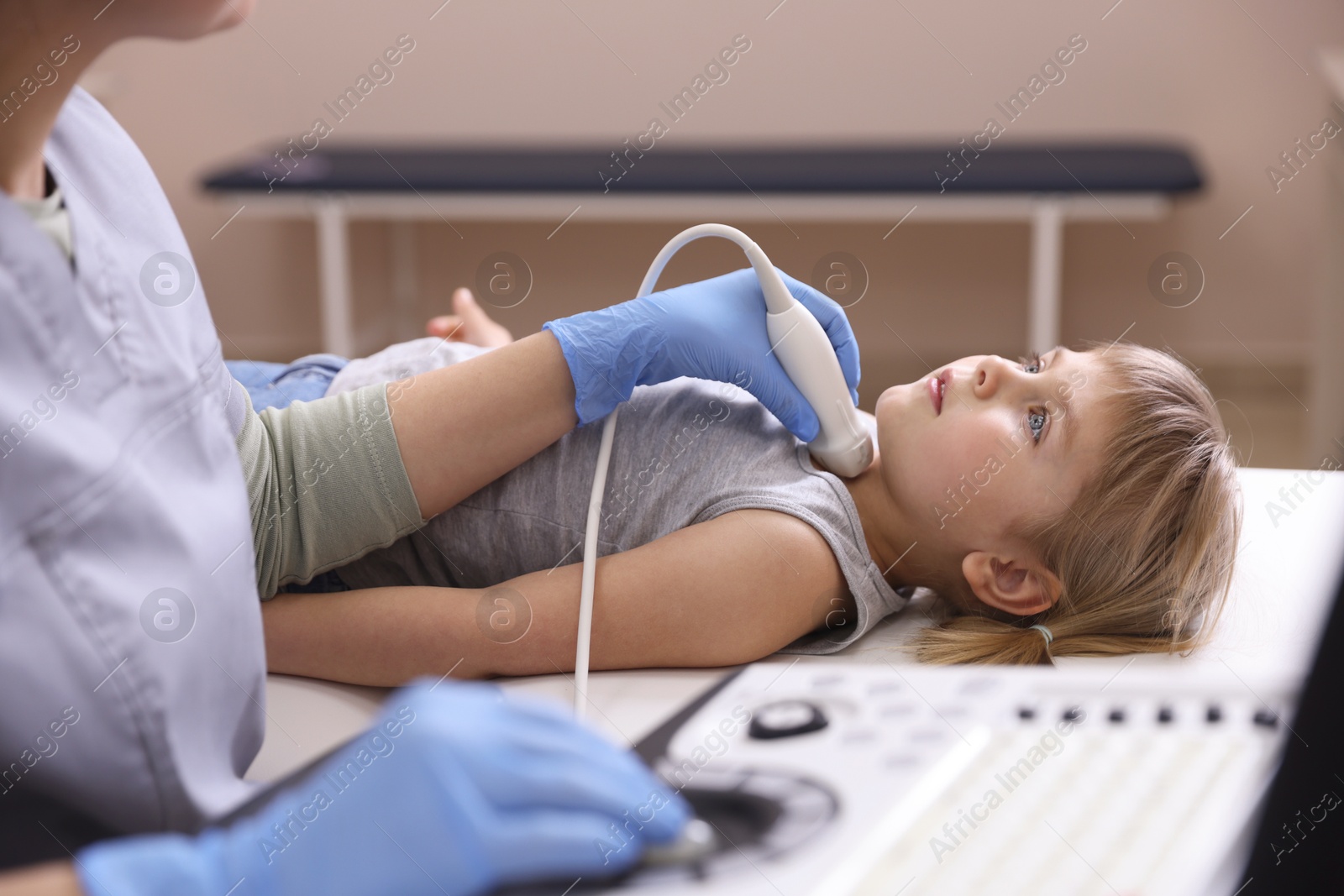 Sonographer conducting ultrasound examination of little girl's thyroid gland in clinic, closeup Photo of Sonographer conducting ultrasound examination of little girl's thyroid gland in clinic, closeup