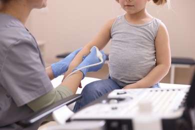 Photo of Sonographer conducting ultrasound examination of little girl's arm in clinic, closeup