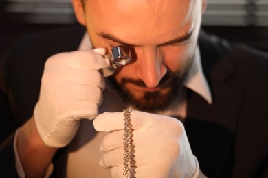 Photo of Appraiser with loupe evaluating luxury jewelry indoors, closeup