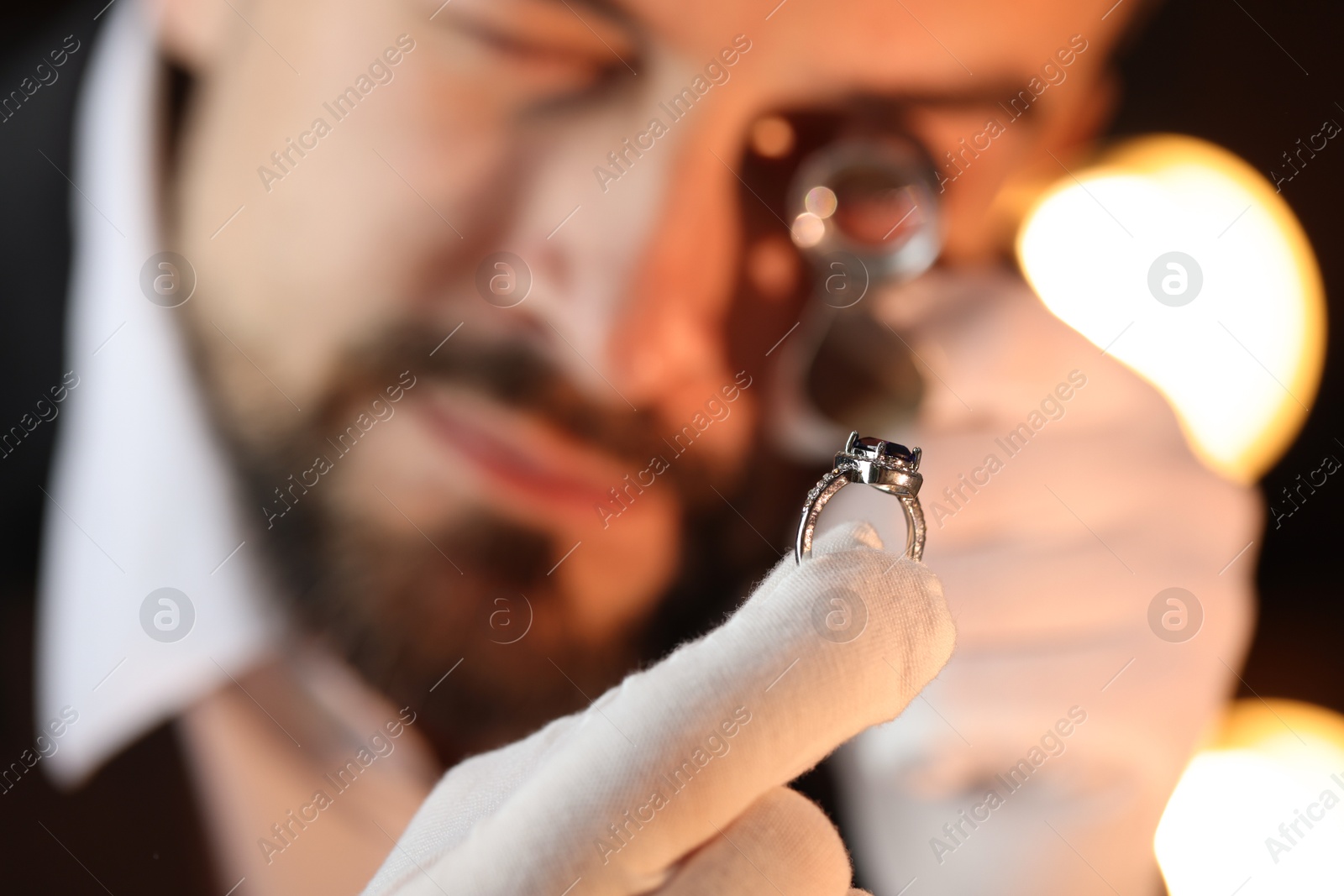 Appraiser with loupe evaluating luxury ring indoors, selective focus Photo of Appraiser with loupe evaluating luxury ring indoors, selective focus