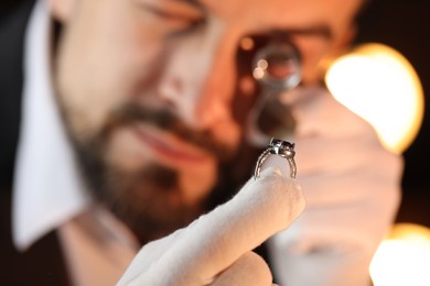 Photo of Appraiser with loupe evaluating luxury ring indoors, selective focus