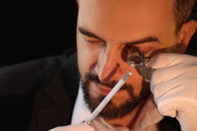 Photo of Appraiser with loupe evaluating luxury gemstone indoors, closeup