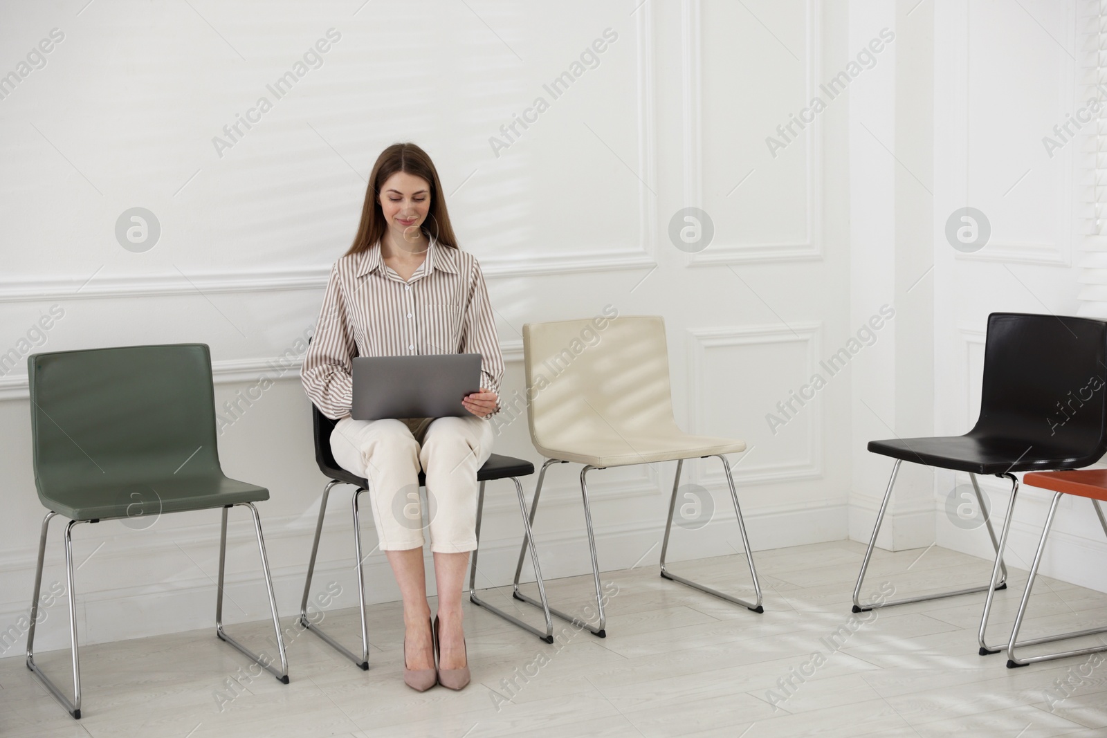 Woman with laptop waiting for appointment indoors Photo of Woman with laptop waiting for appointment indoors