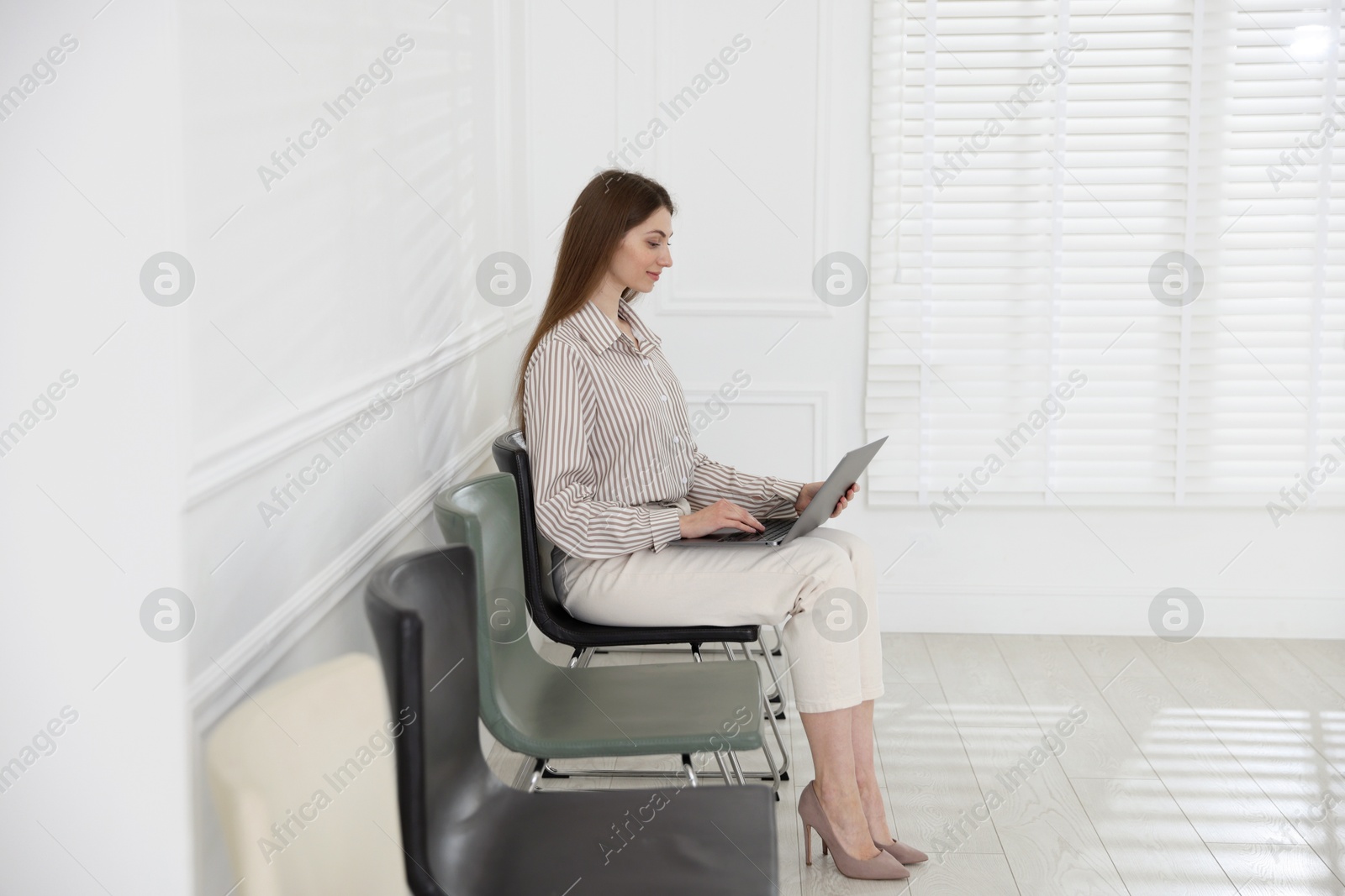 Woman with laptop waiting for appointment indoors Photo of Woman with laptop waiting for appointment indoors